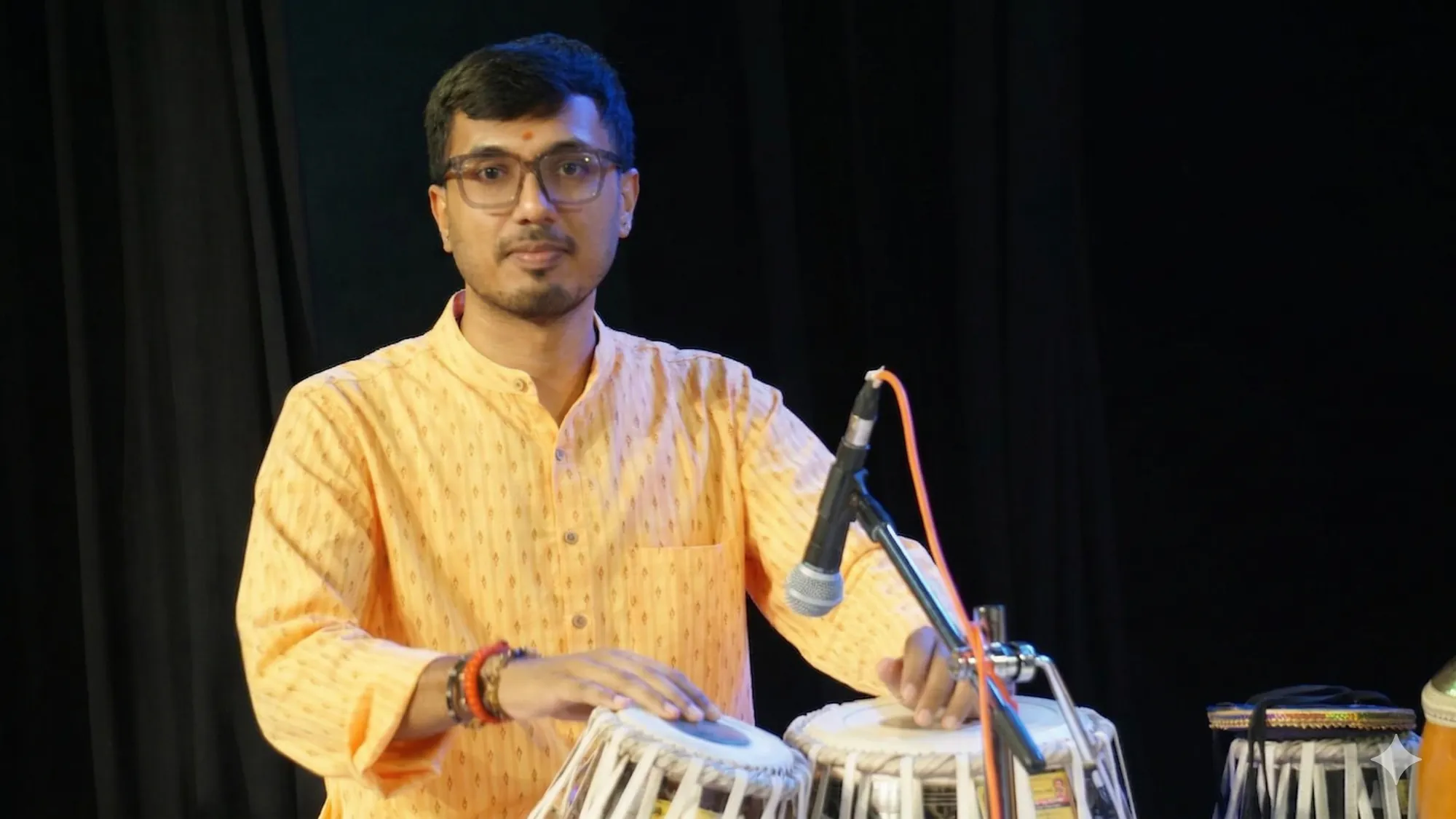 Kaushik Bhat performing a tabla recital under stage lights